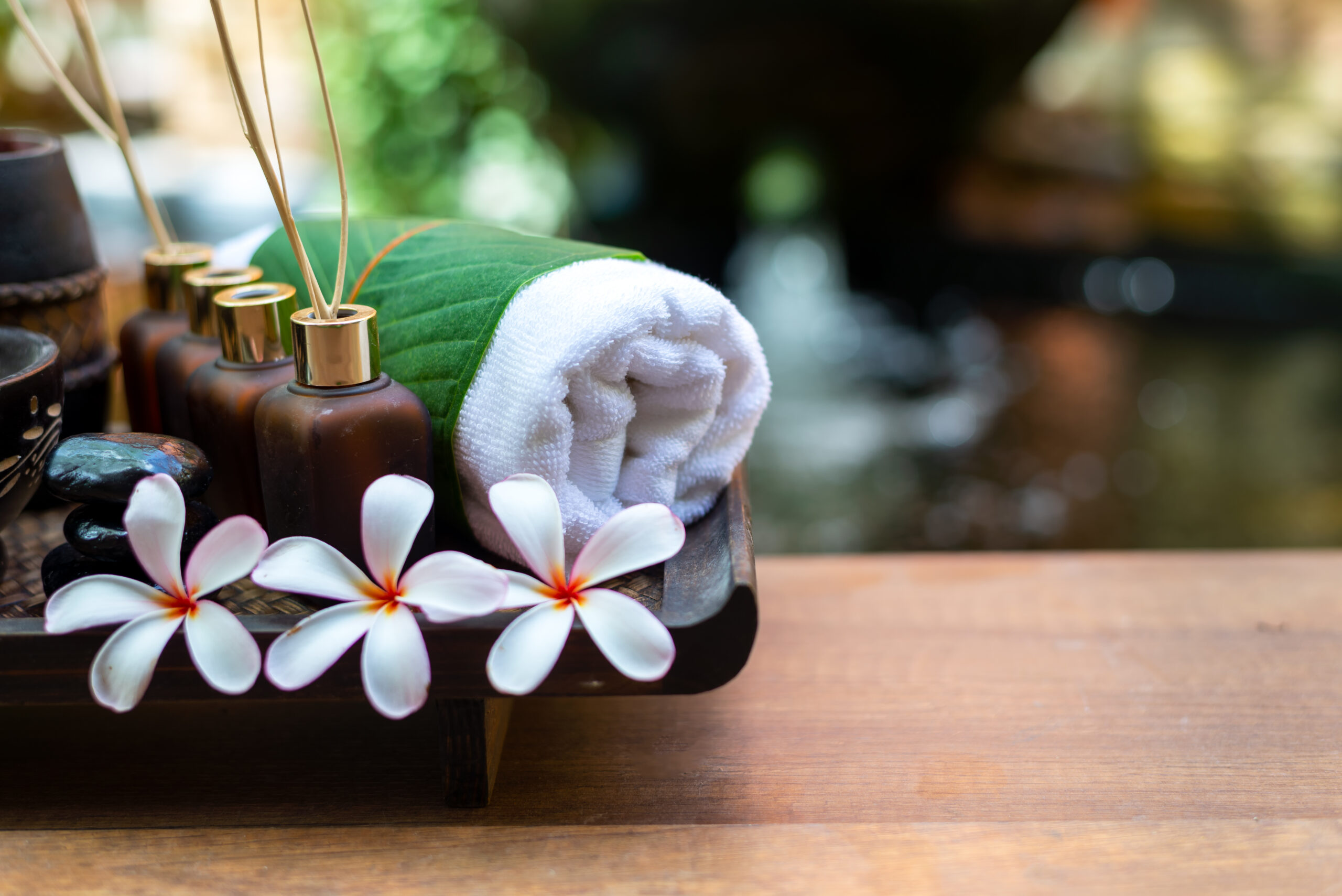 thai spa composition treatments aroma therapy with candles and plumeria flowers on wooden table close up. healthy and relax concept.
